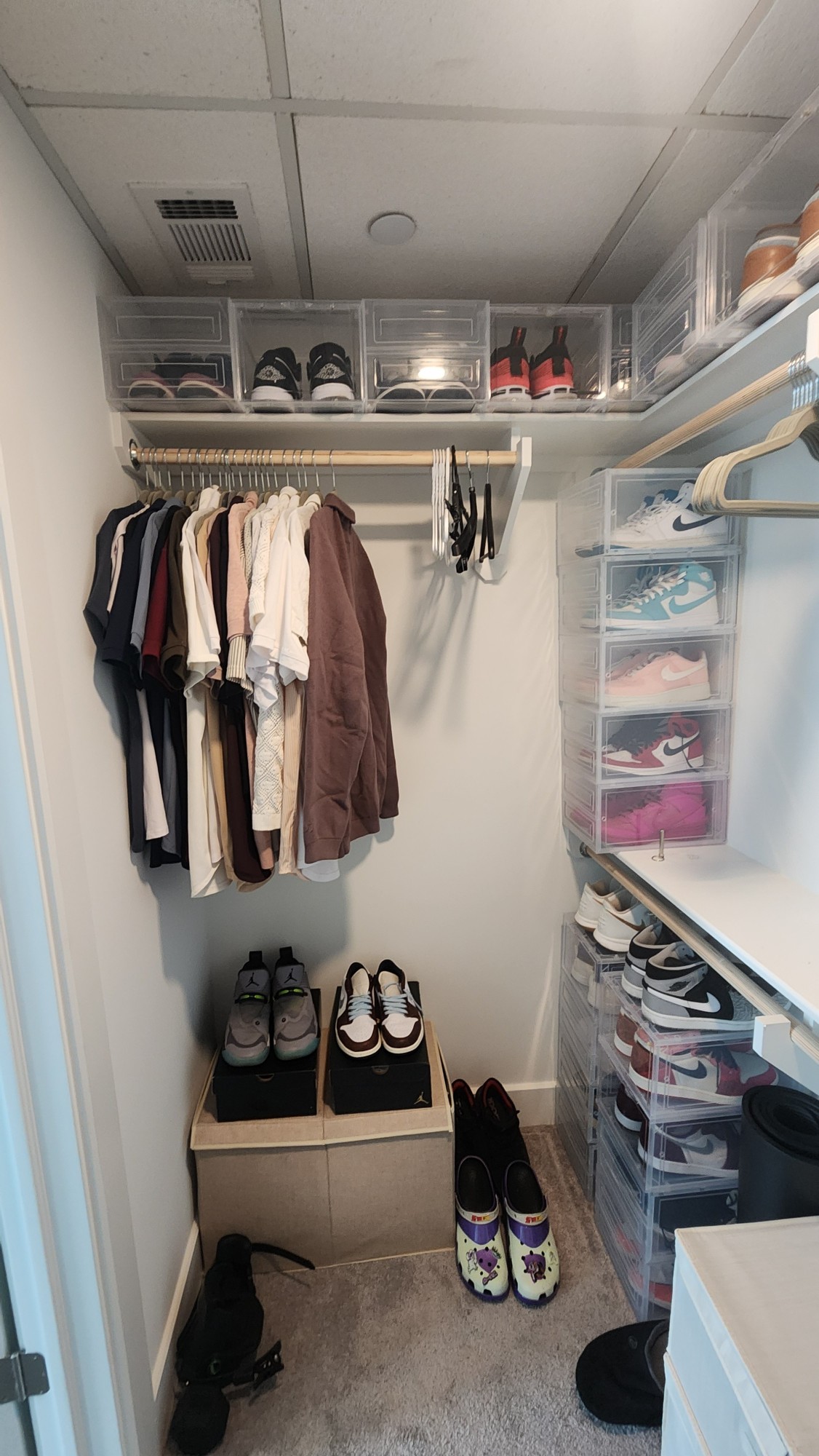 Organized walk-in closet with clear shoe boxes and hanging clothes, by Fouro Living